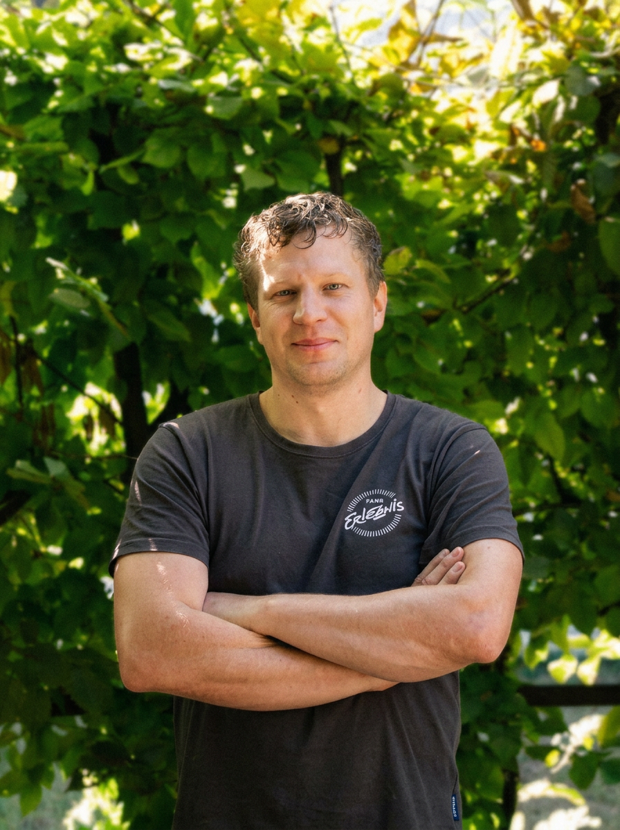 Portrait von Roman Kassowitz vor grüner Hecke